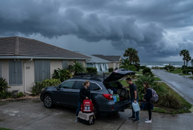 Hurricane evacuation guide: family securing home and packing go-bag before a coastal storm